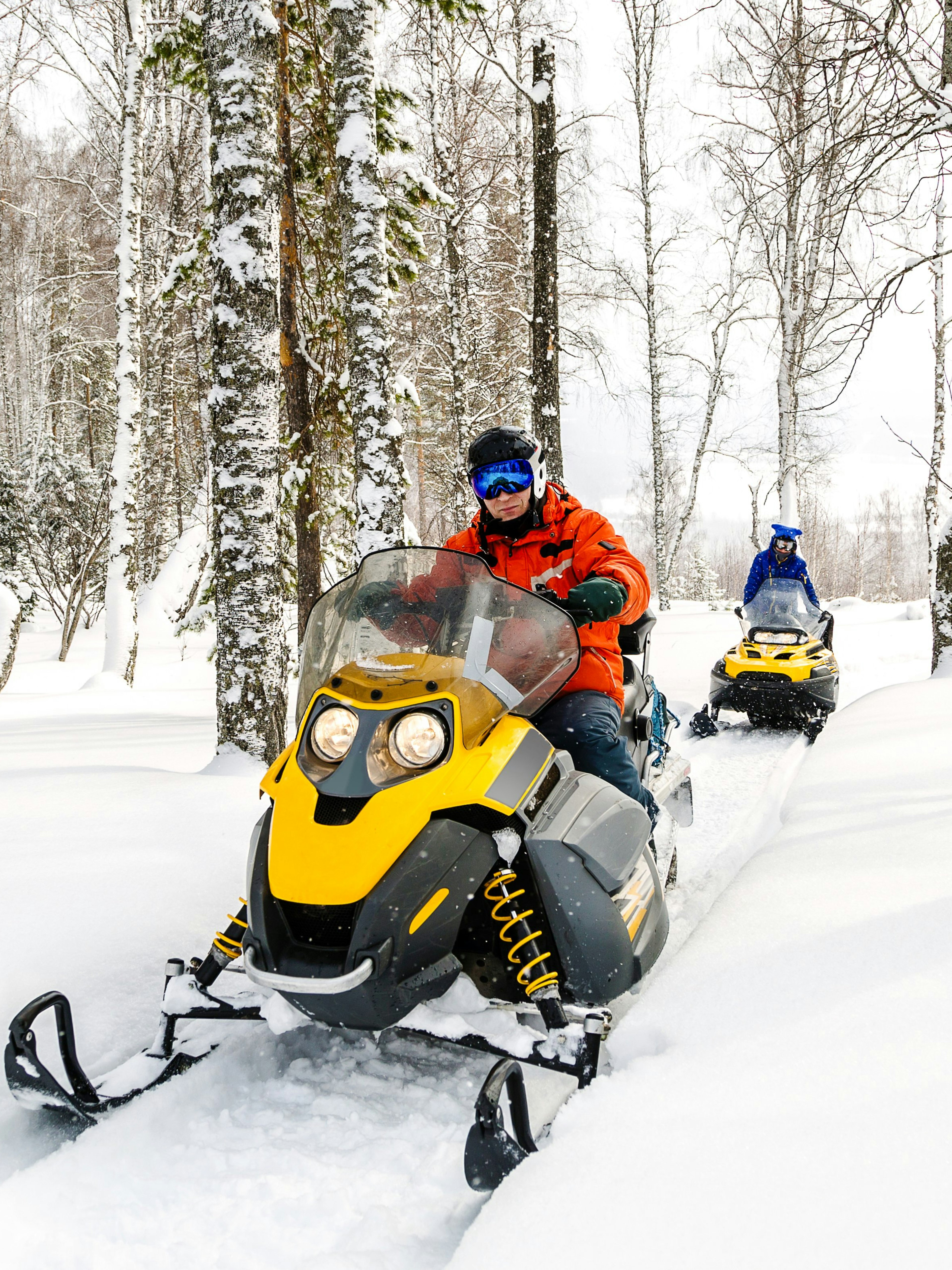 Man riding snowmobile through snowy forest in Lapland.