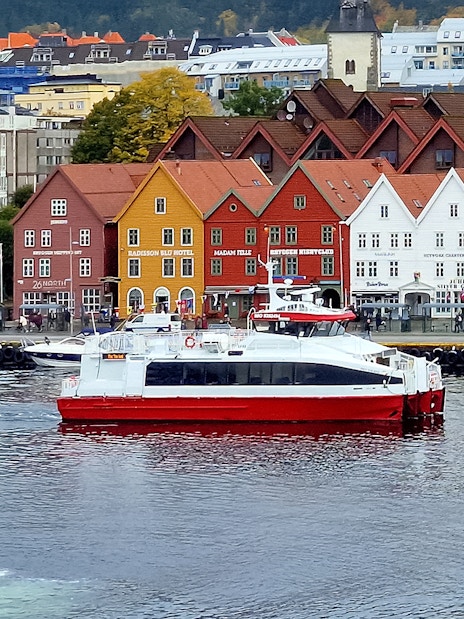 Sightseeing cruise boat in front of colorful historic buildings in Bergen, Norway.