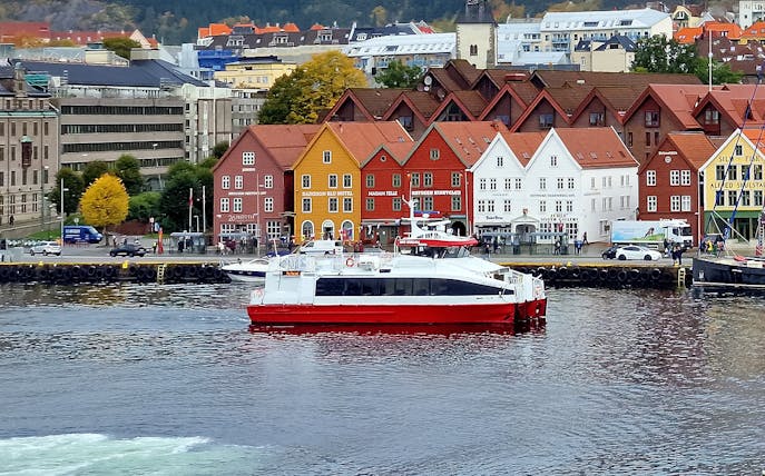 Sightseeing cruise boat in front of colorful historic buildings in Bergen, Norway.