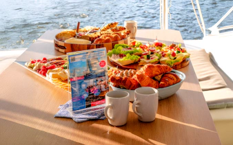 Breakfast spread on catamaran cruise from Gdansk with pastries, cheese, and coffee.