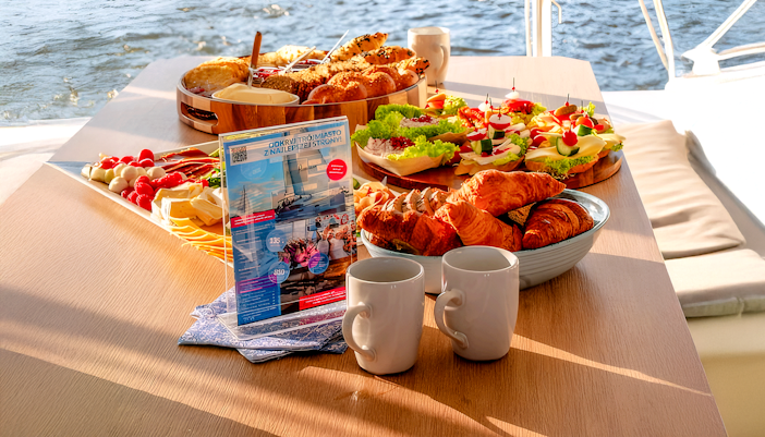 Breakfast spread on catamaran cruise from Gdansk with pastries, cheese, and coffee.