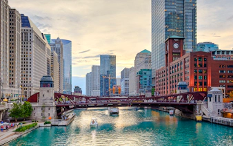 Chicago River with boats and iconic skyscrapers in downtown Chicago.