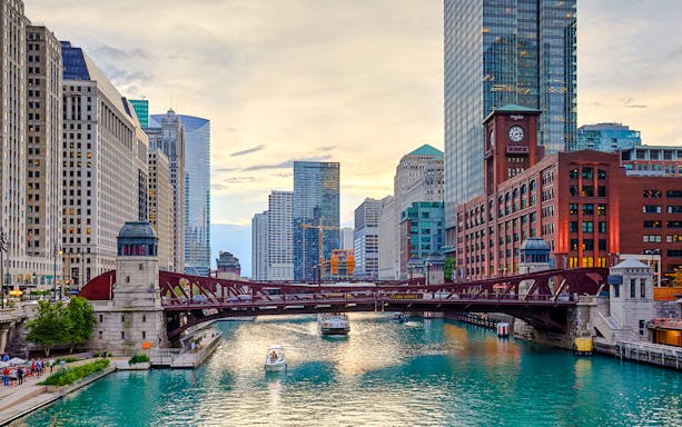 Chicago River with boats and iconic skyscrapers in downtown Chicago.