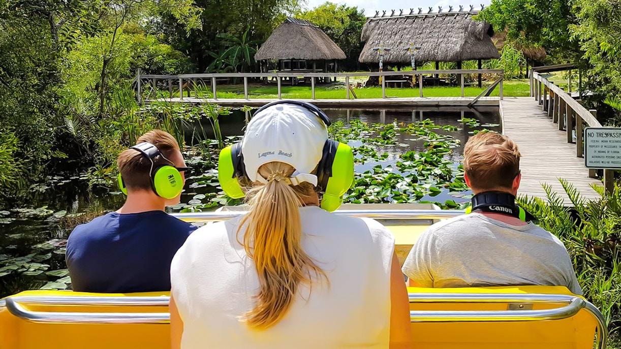 Airboat ride through Everglades with guests observing wildlife and lush scenery.