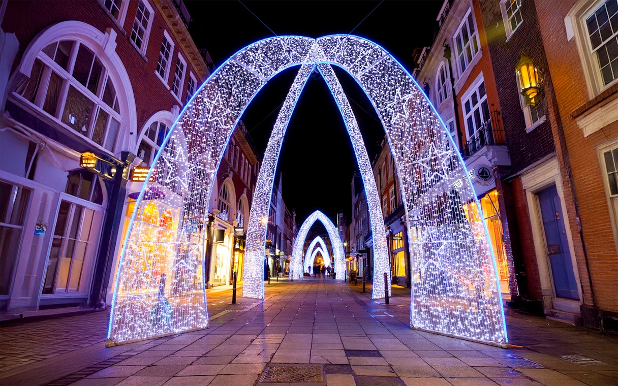 London street adorned with illuminated Christmas arches at night.