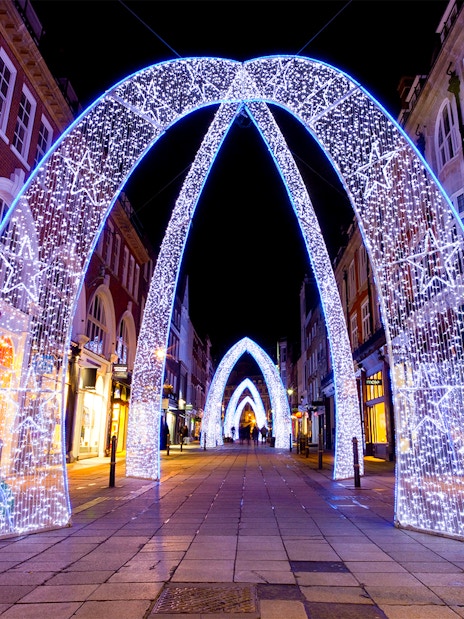 London street adorned with illuminated Christmas arches at night.