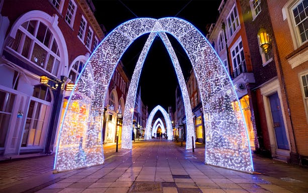 London street adorned with illuminated Christmas arches at night.
