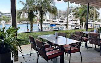 Outdoor dining area overlooking marina with yachts, part of YachtCruiseSG Speedboat Cruise & Marina Dining Combo.