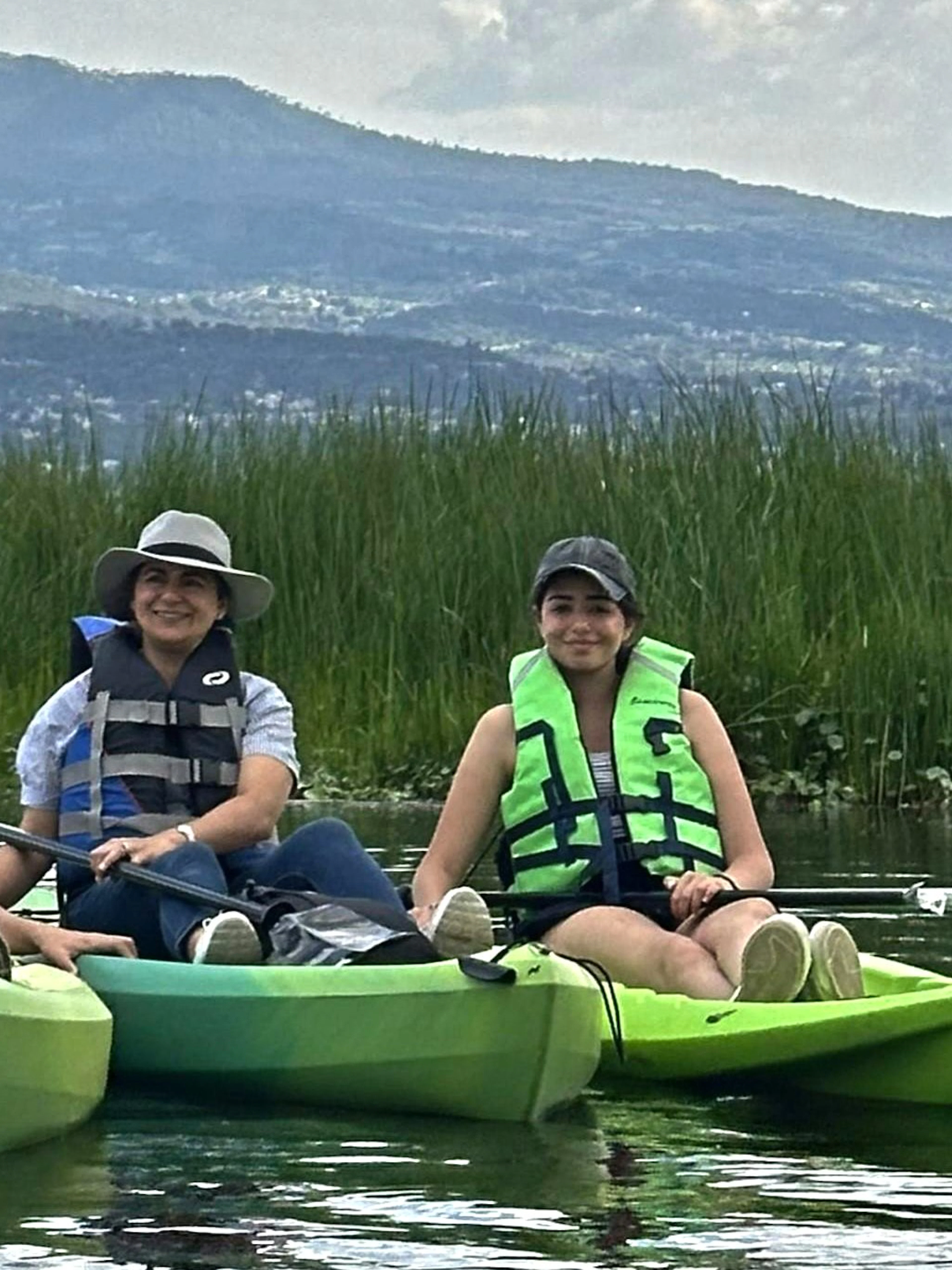 Group kayaking on Xochimilco canal with local guide, surrounded by lush greenery.