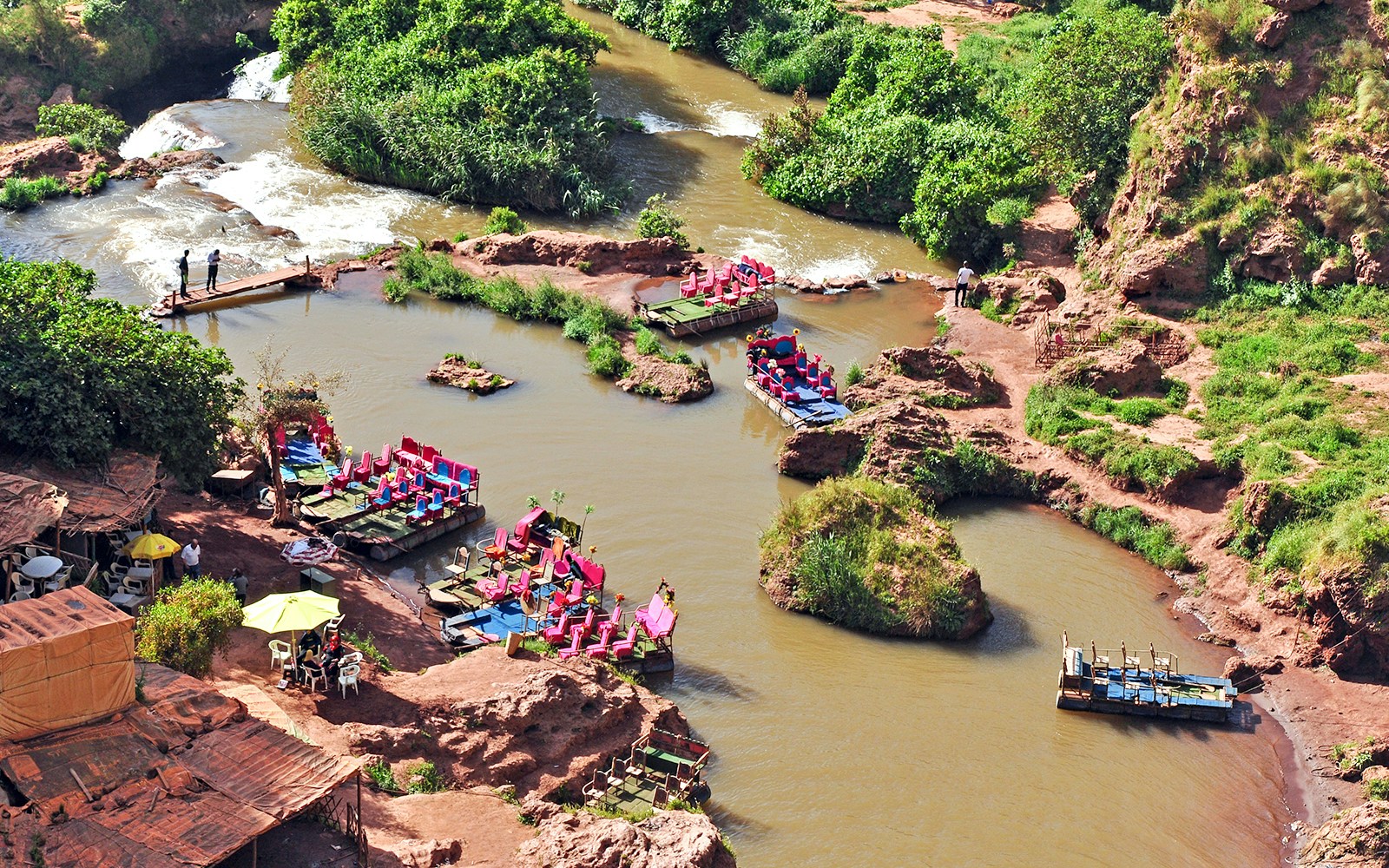 Boats on a river in Cascade D Ouzoud Valley, Morocco, surrounded by lush greenery and rocky terrain.