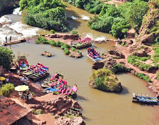 Boats on a river in Cascade D Ouzoud Valley, Morocco, surrounded by lush greenery and rocky terrain.