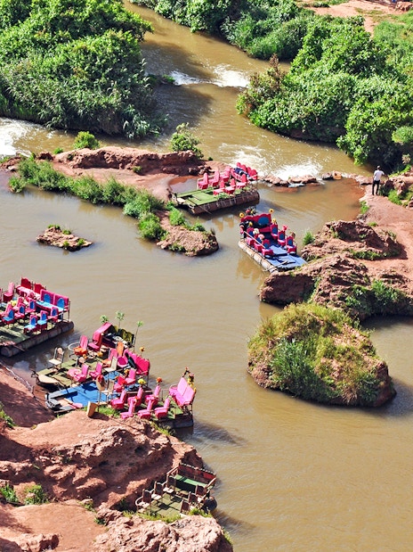 Boats on a river in Cascade D Ouzoud Valley, Morocco, surrounded by lush greenery and rocky terrain.