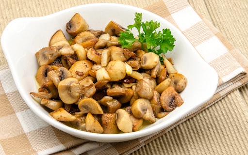 Sautéed mushrooms with parsley garnish on a white dish, featured in St. Georg kulinarisch food tour.