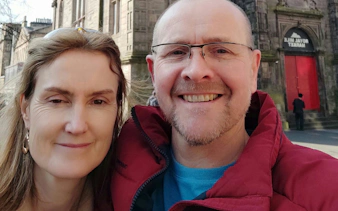 Couple smiling in front of Royal Mile Market entrance, Edinburgh.