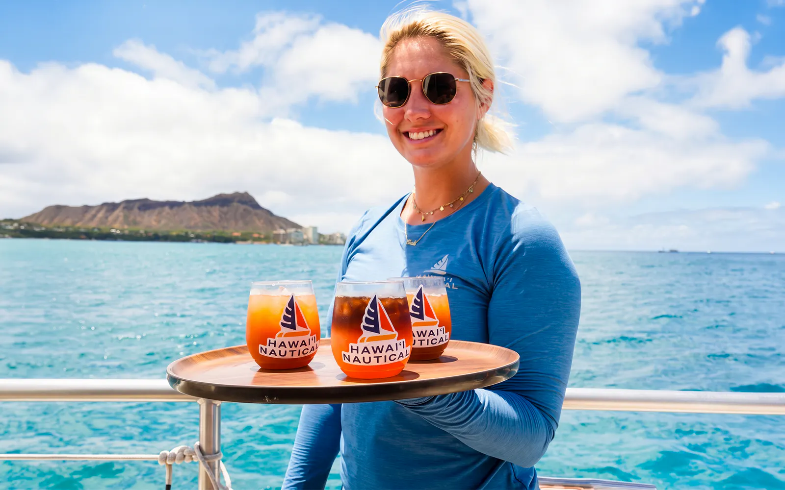 Server holding drinks on Kaula Kai Sunset Sail with Diamond Head in background, Oahu.