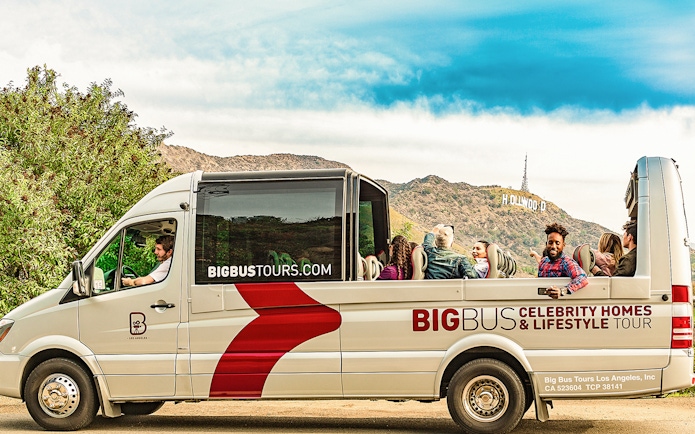 Open-top bus on Celebrity Homes Tour with Hollywood Sign in Los Angeles.