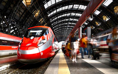 Trenitalia Frecciarossa train at a bustling station platform.