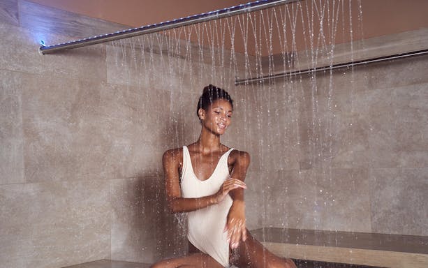 Person enjoying a rain shower at QC New York spa.