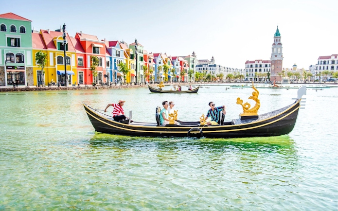 Gondola ride in Venice with colorful buildings and a bell tower in the background.