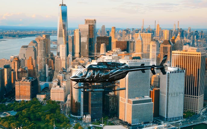 Helicopter flying over New York City skyline with One World Trade Center in view.