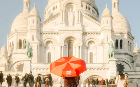Sacre-Coeur Basilica with tourists and a red umbrella on the Emily in Paris Montmartre Walking Tour.