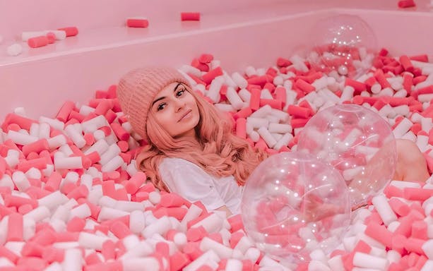 Person relaxing in a pink and white foam pit at Be Happy Museum, Zakopane.