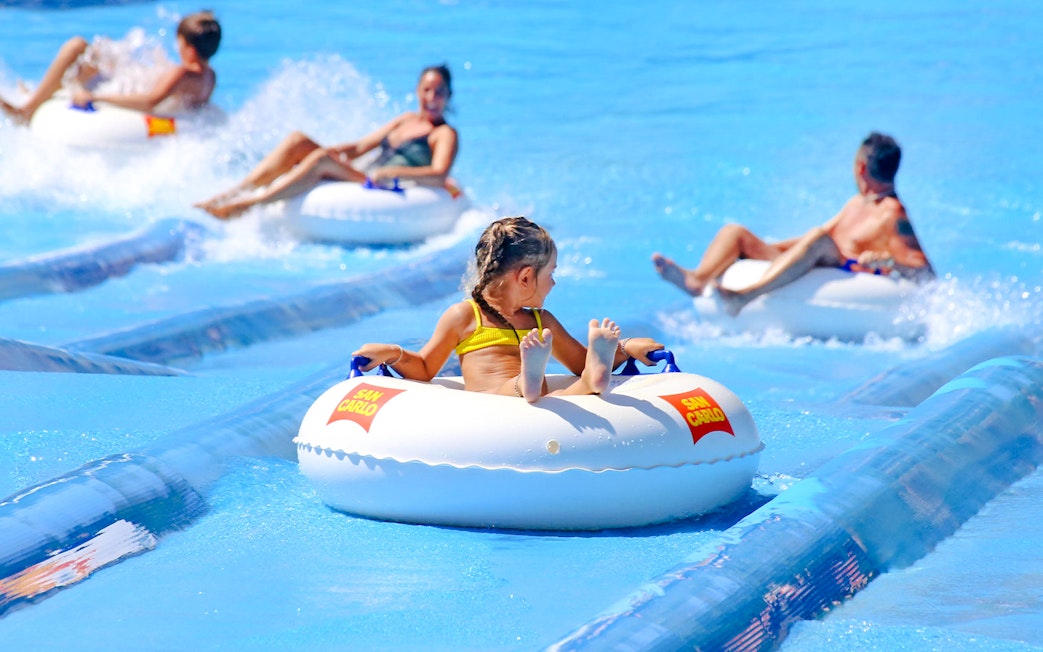 Children and adults enjoying water slides at Aquafan Water Park.