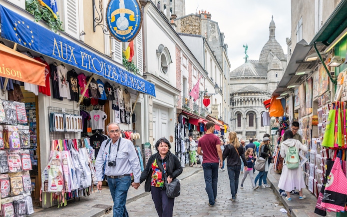 Tourists walking through Montmartre with Sacré-Cœur Basilica in the background, Paris.