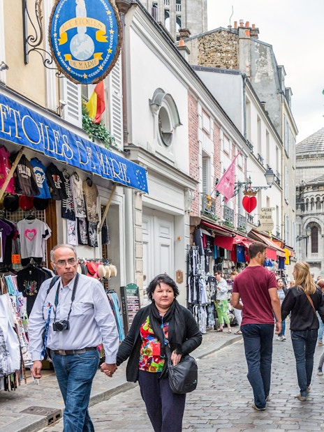 Tourists walking through Montmartre with Sacré-Cœur Basilica in the background, Paris.