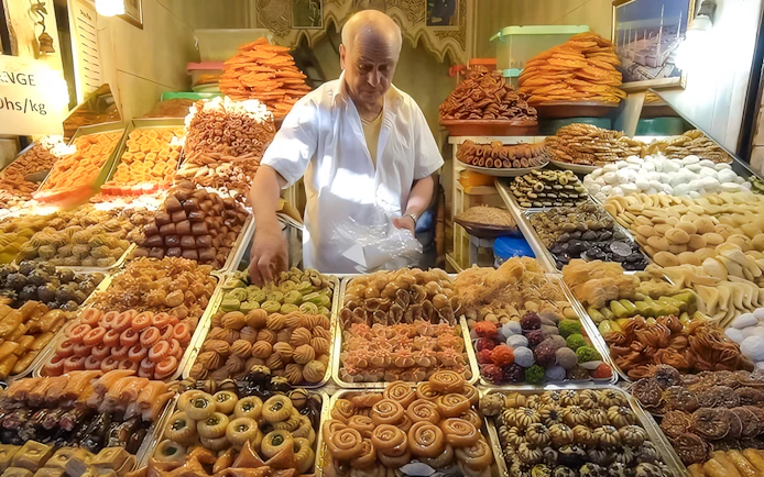 Vendor arranging traditional sweets at Jema el Fna street food market in Marrakesh.