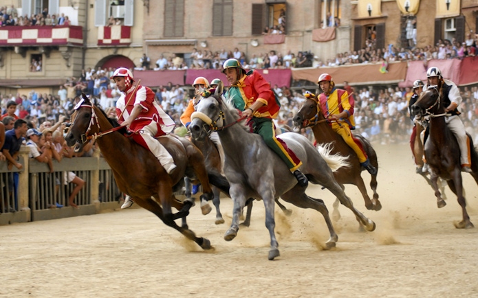 Horse race at Siena's Palio, Tuscany, with riders in colorful attire.