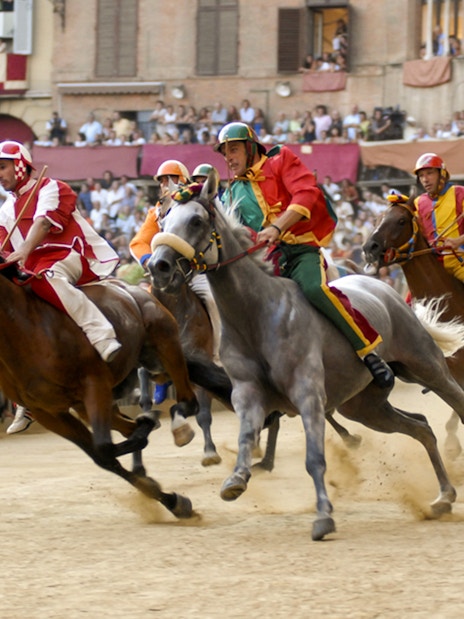 Horse race at Siena's Palio, Tuscany, with riders in colorful attire.