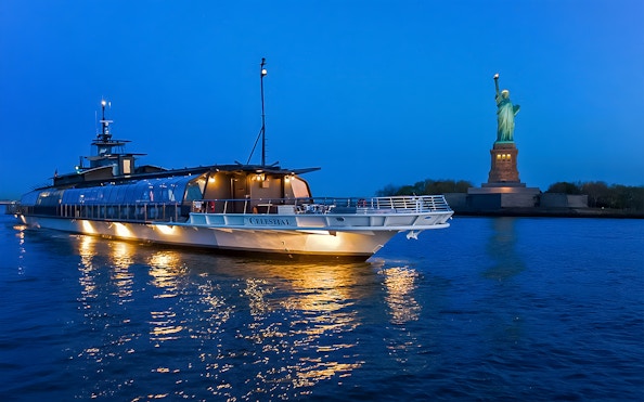 Bateaux Premier Dinner Cruise near Statue of Liberty at dusk.