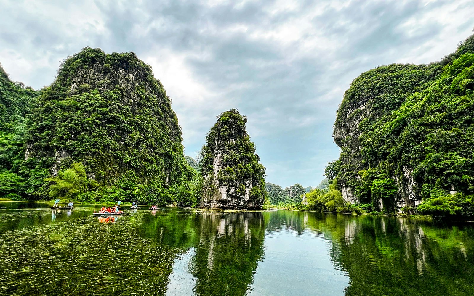 Boats on the river surrounded by limestone karsts at Tràng An Scenic Landscape Complex, Ninh Bình, Vietnam.