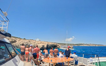 Tourists enjoying a Blue Lagoon cruise near rocky coastline in Larnaca, Cyprus.