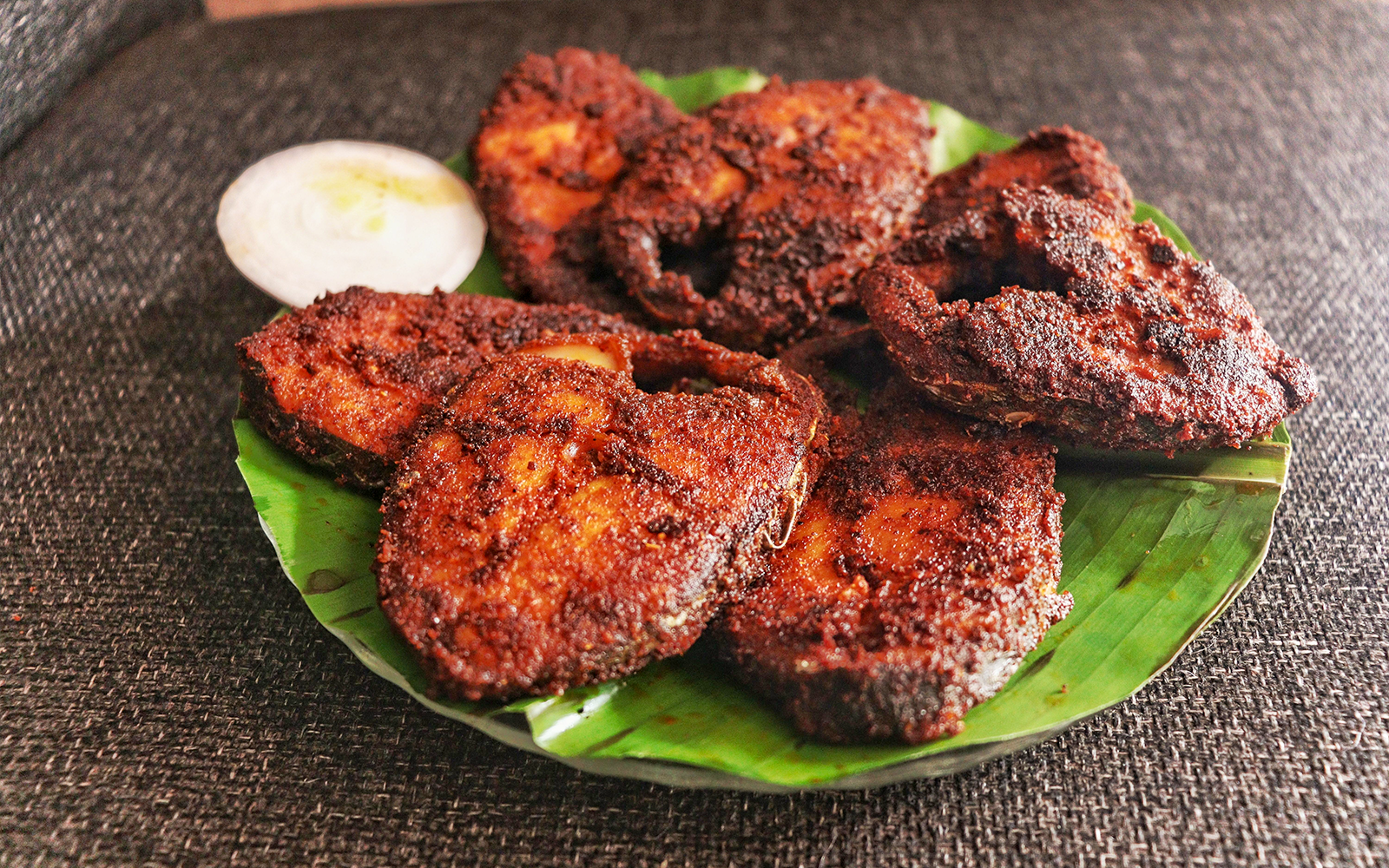 Grilled fish on a banana leaf with onion slice, Jimbaran Bali seafood dinner.
