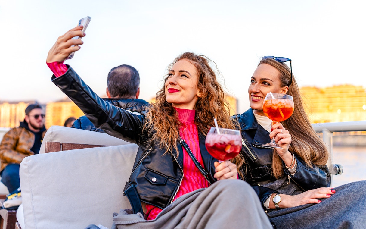 Guests taking selfies with drinks on Elegant Premium Sightseeing Cruise.
