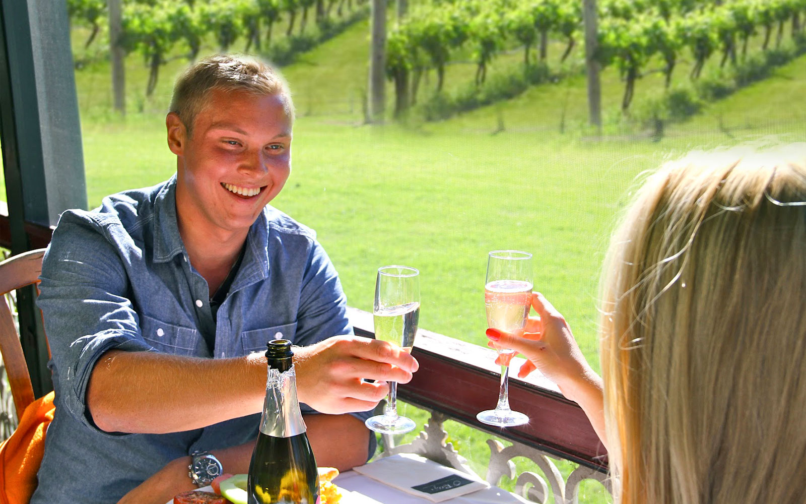 Couple toasting with champagne at a vineyard breakfast in Brisbane.