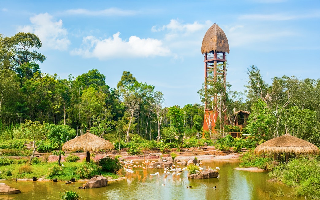 Vinpearl Safari lake with flamingos and observation tower amidst lush habitats.