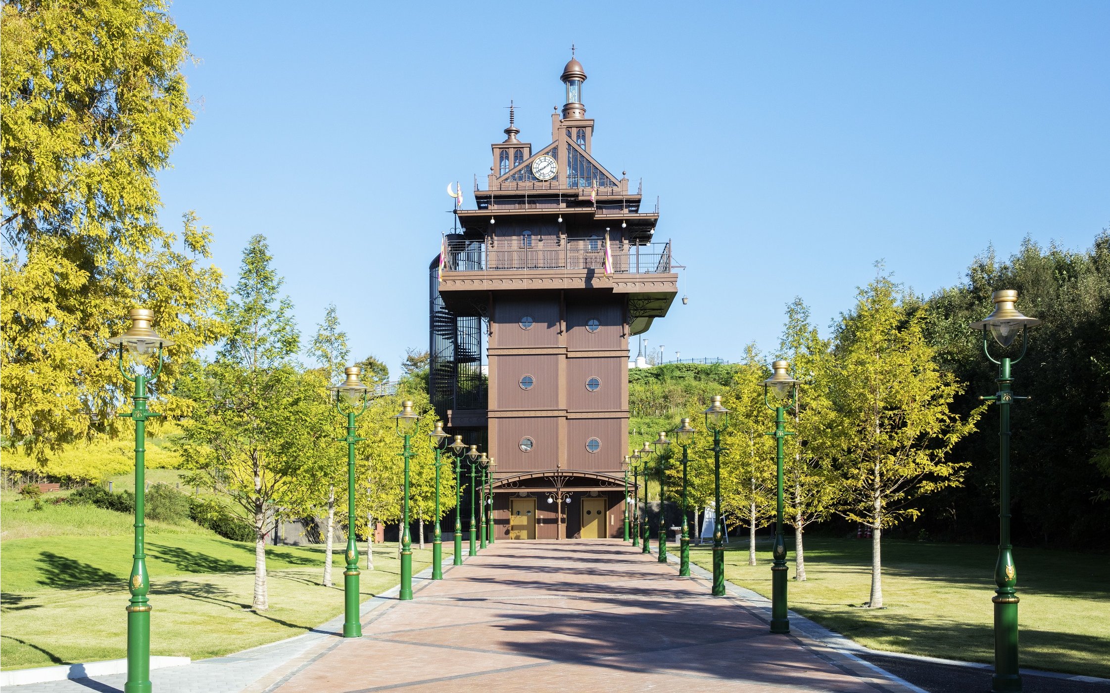 Elevator tower with clock and green lampposts in a landscaped park.