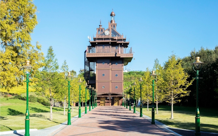 Elevator tower with clock and green lampposts in a landscaped park.