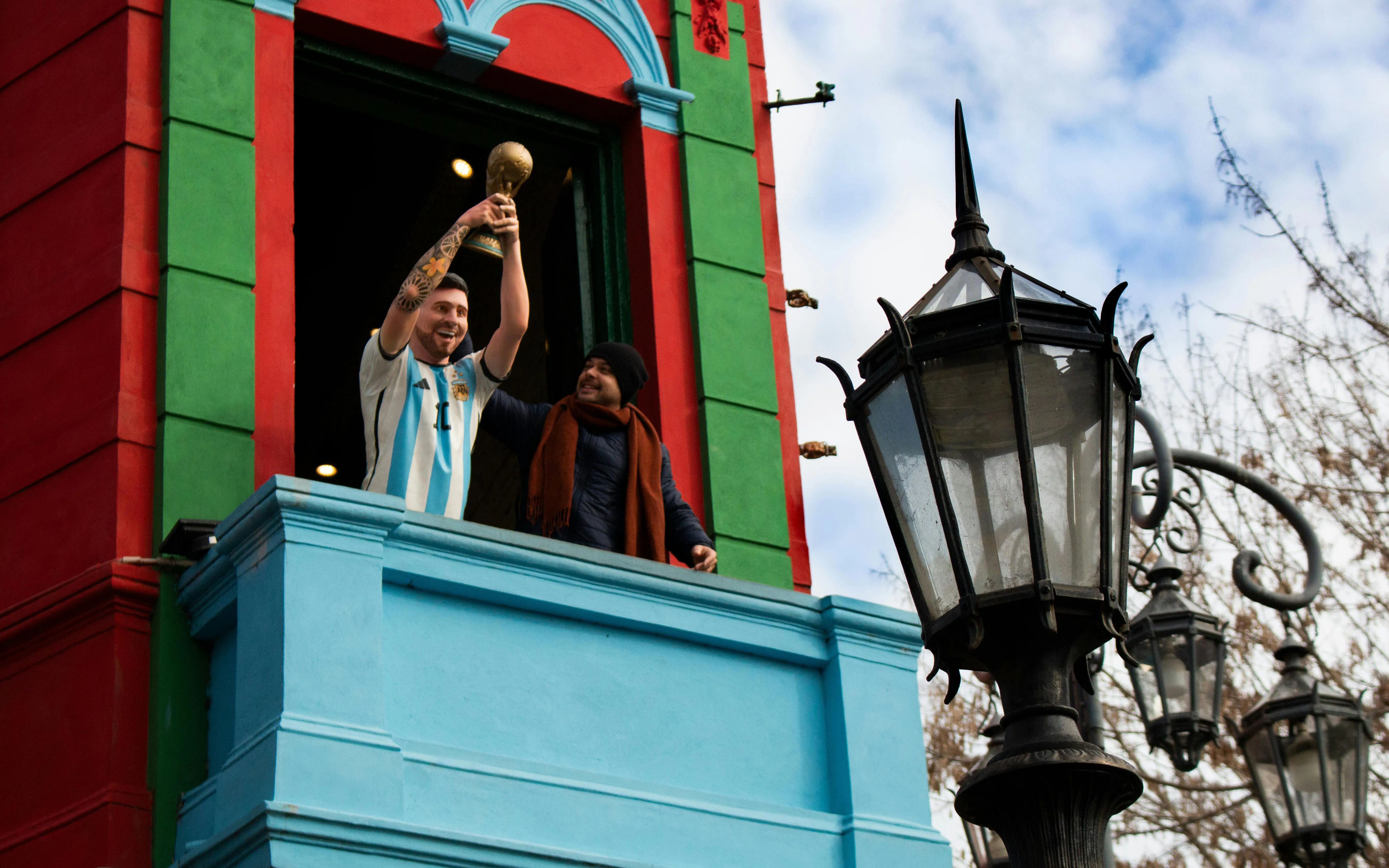 Statue of Lionel Messi holding a trophy on a colorful balcony in Caminito, La Boca, Buenos Aires.