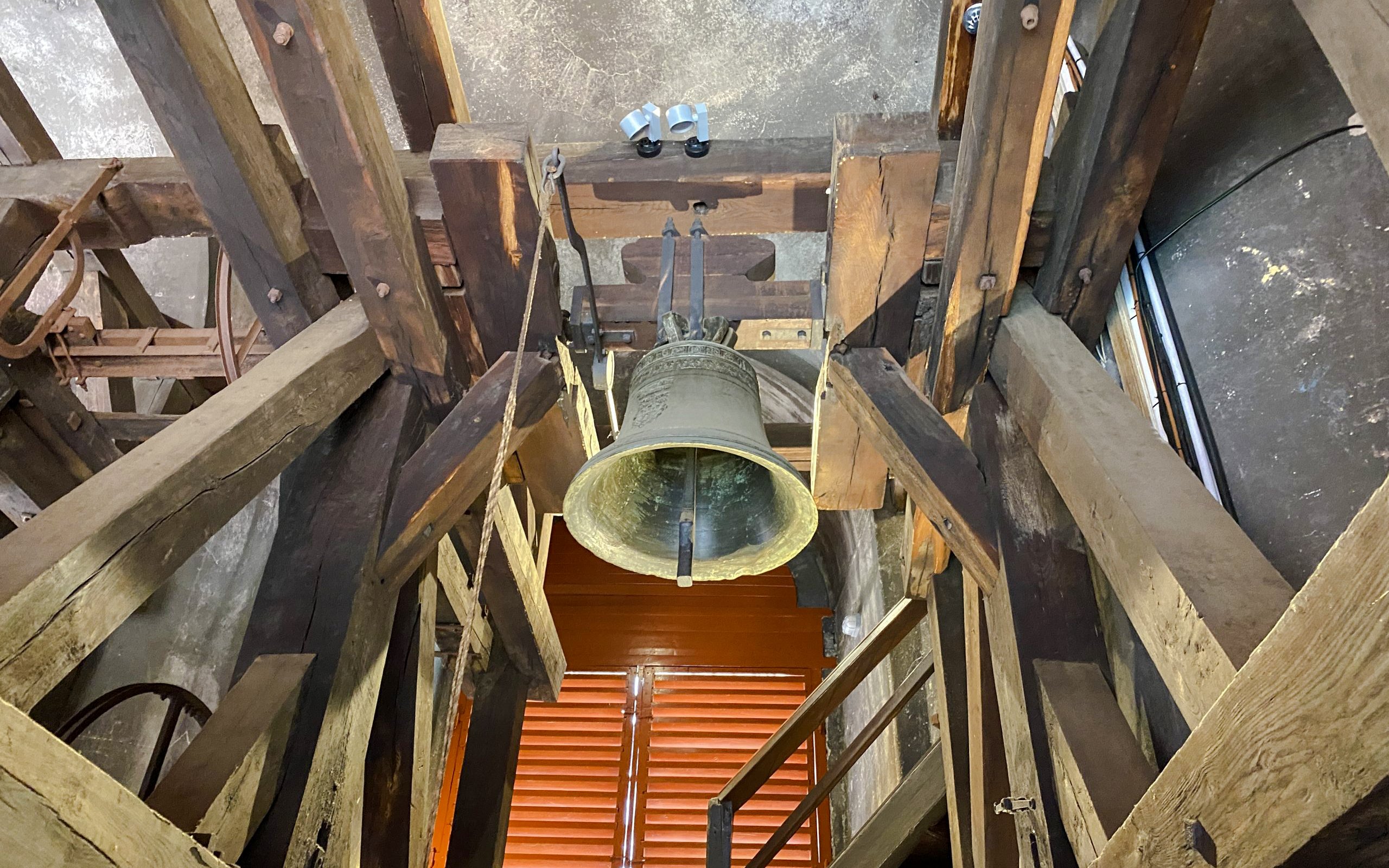 Bell inside St. Nicholas Bell Tower, Prague, surrounded by wooden beams.