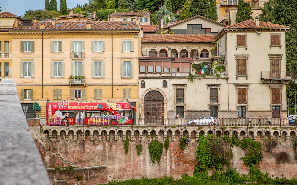 Verona sightseeing bus passing historic buildings on a hop-on hop-off tour.