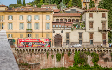 Verona sightseeing bus passing historic buildings on a hop-on hop-off tour.