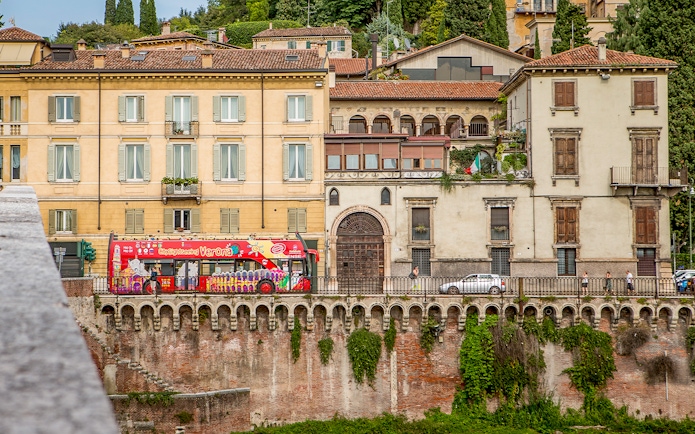 Verona sightseeing bus passing historic buildings on a hop-on hop-off tour.