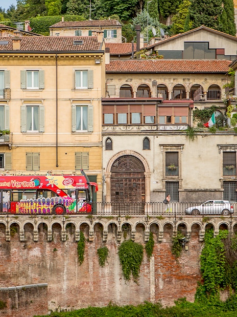 Verona sightseeing bus passing historic buildings on a hop-on hop-off tour.
