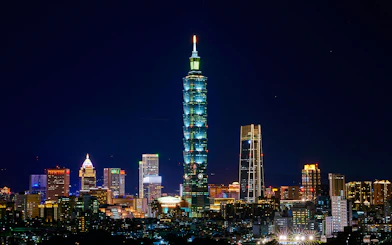 Taipei 101 illuminated at night, surrounded by cityscape in Taipei, Taiwan.
