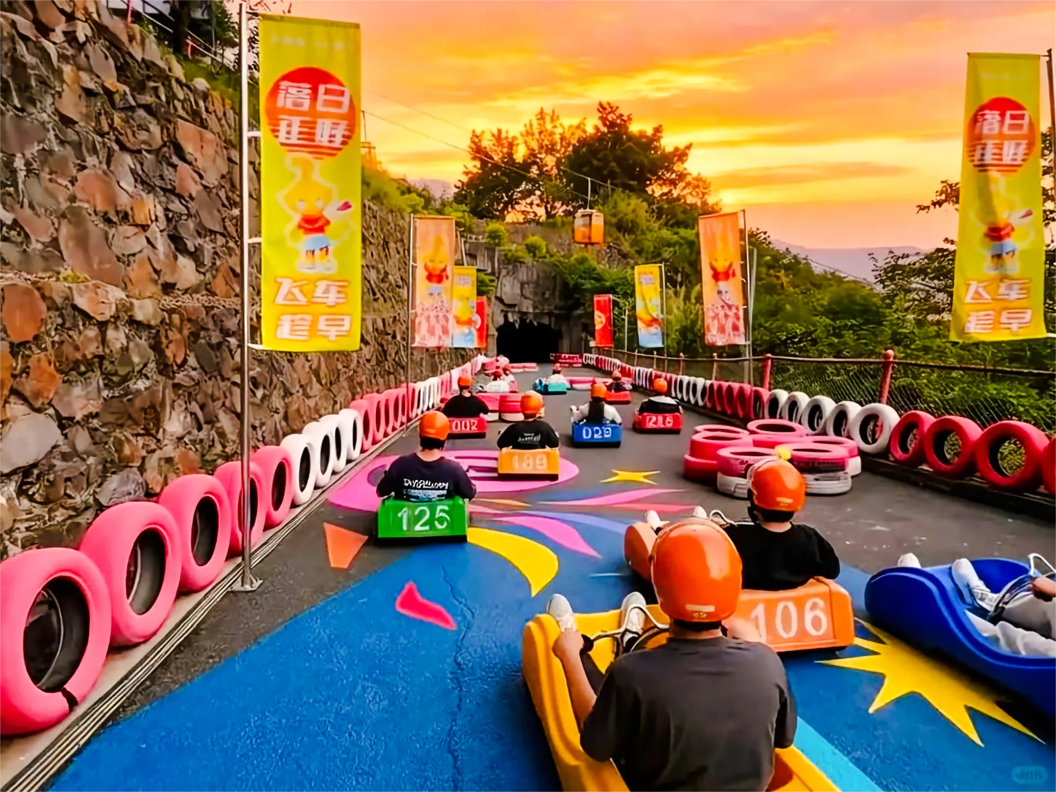 Visitors riding alpine slide carts at Huangteng Gorge, Guangzhou, with colorful track and sunset backdrop.