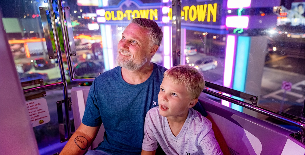 Guests enjoying a ride at Old Town, Orlando with neon lights in the background.